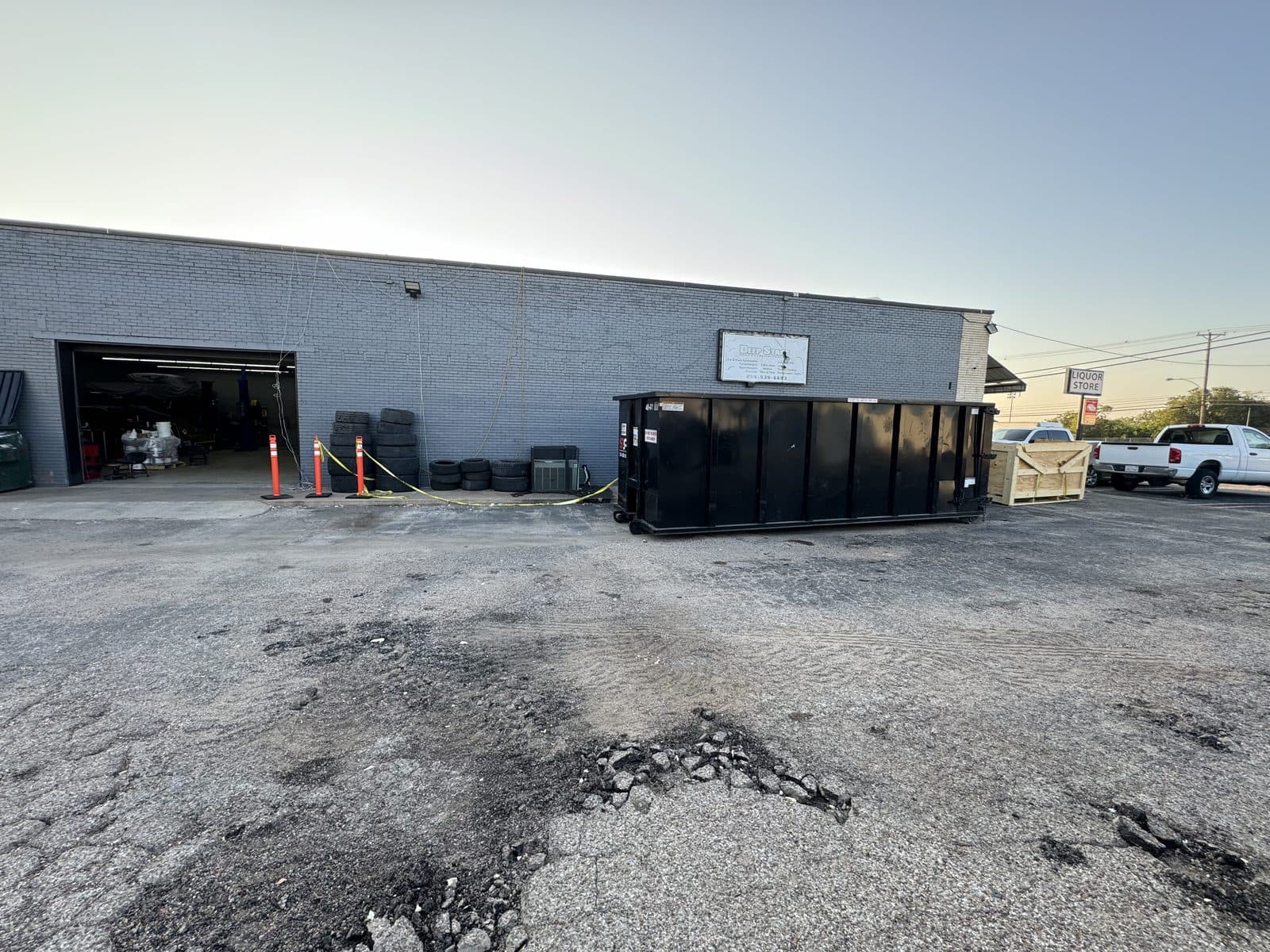 A 30 yard S&P container at a commercial shop with broken-out asphalt and demolition debris beside it