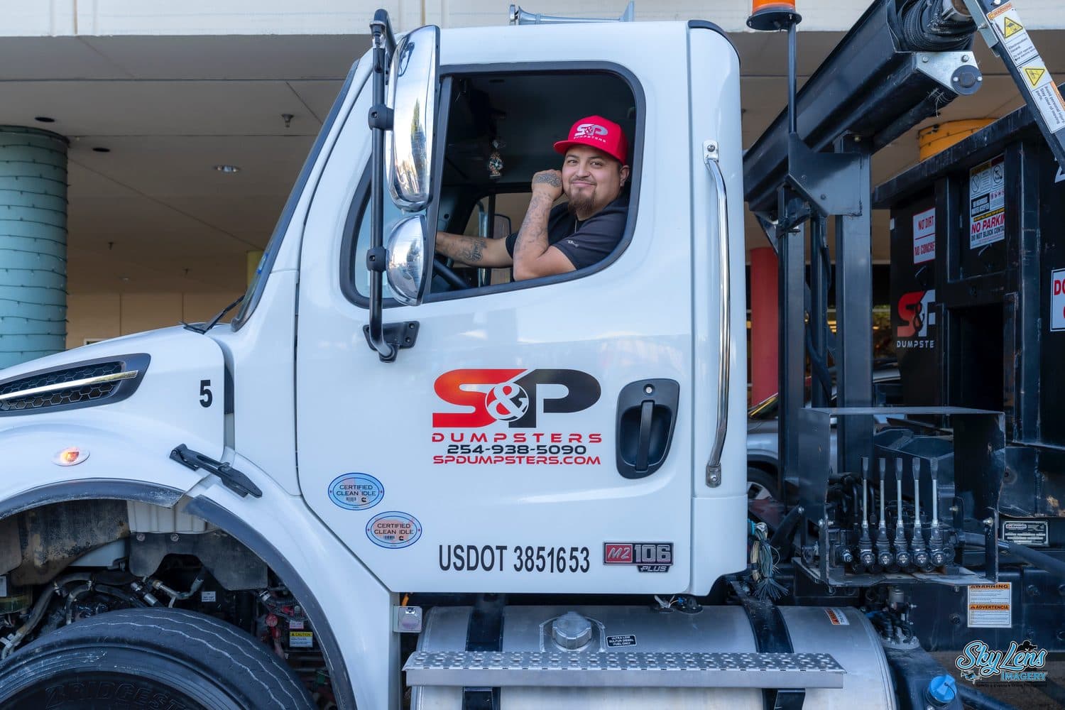 An S&P Dumpsters driver in the cab of a company roll-off truck