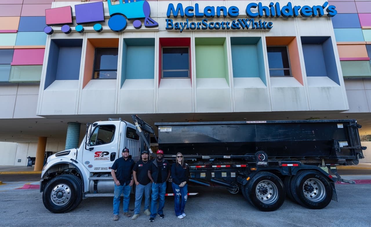 The S&P Dumpsters team in front of a company roll-off truck at McLane Children's Medical Center